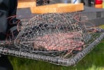 Nick Atwell holds one of the humane wire traps, about the size of large textbook, built by the wildlife team to capture raptors at the Portland International Airport.