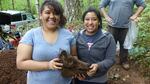 Zairet Solis and Daisy Romero hold a root-bound pig skull they just exhumed.