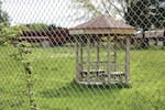 One of two small gazebos built on the Chemawa campus sits behind a fence.
