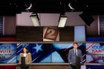 Two candidates stand on stage at a news station and take questions during a Washington Congress debate.