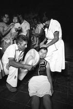 The sister of a civil defenseman, center, faints upon hearing of the death of her brother during an overnight attack on the civil defense post in Santa Clara, El Salvador, July 1982. (Photo by Robert Nickelsberg/Getty Images)