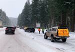 FILE PHOTO: A seasonal business offers chain-up help as motorists put snow chains on their tires in November 2019 before driving over snowy Santiam Pass, Ore.