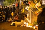 Vigil attendees light candles at a fence in the back of the bank branch on Oct. 30 in memorial of Kevin Peterson Jr. Peterson was shot and killed by Clark County Sheriff's Office deputies the night before.