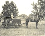 A Wenatchee Sprayer made by A. D. Browning, Wenatchee. Two men, one with bamboo spray pole, and one small boy sitting on top of sprayer pulled by one horse in a fruit orchard in Wenatchee. Because farmers did not know of the potential toxicity or longevity of pesticides in use at the time, Washington law exempts farmers from being liable for contamination from legally applied pesticides.