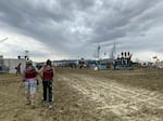 Burning Man attendees walk through a muddy desert plain on Saturday, after heavy rains pelted the annual Nevada festival.