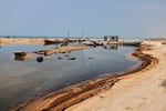 Oil residue lines the shore near fishing boats on Qeshm Island, Iran, Thursday, Aug. 13, 2026, amid ongoing wartime attacks on vessels and infrastructure in and around the Strait of Hormuz, though the spill's source has not been independently determined.