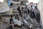 People gather outside a collapsed building as they attempt to extricate a man from underneath the rubble following Israeli bombardment in the Saftawi district in Jabalia in the northern Gaza Strip on October 15.