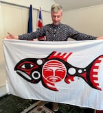 Kaye holds up the Chinook Indian Nation flag. Kaye has supported many tribes with the process of designing their flags. He wrote the book "Flags of the Native Peoples of the United States."