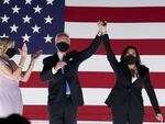 In 2020, former Vice President Joe Biden, Democratic presidential nominee, and Sen. Kamala Harris, Democratic vice presidential nominee, wear protective masks while holding hands next to Jill Biden, left, outside the Chase Center during the Democratic National Convention in Wilmington, Del.