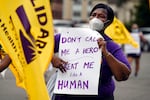 A demonstrator holds a sign that says "Don't call me a hero, treat me like a human."