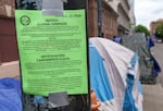 FILE - An illegal camping notice is posted near a group of tents in downtown Portland, Oregon, on May 20, 2022.