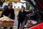 Volunteer Aaron Xavier, left, helps load food for William Yee, center, at One Life Food Pantry, located in Real Life Foursquare Church in Vancouver, Wash., on Nov. 1, 2025. Yee not only picked up food for himself and his disabled partner, but also for two coworkers.