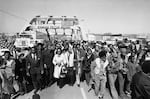 Aided by Father James Robinson, Mrs. Coretta Scott King, widow of Dr. Martin Luther King, Jr., center, and John Lewis of the Voter Education Project, a crowd estimated by police at 5,000, march across the Edmund Pettus Bridge from Selma, Alabama March 8, 1975.