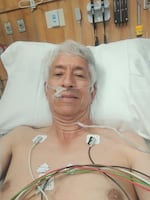 David Loftus lies on the hospital bed with heart monitors and oxygen tubes on his body, Aug. 22, 2025.