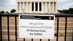 A sign posted in front of a stone monument reads "Because of the federal government shutdown all national parks are closed."