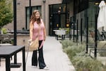 Christina Cooley, who requires a cane to walk and is on disability, walks through the courtyard of The Laureate, where rents typically range from about $1,335 for a smaller one-bedroom — far below the county median — to $3,885 for a larger two-bedroom.