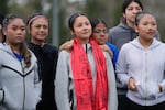 FILE - Samira Abdul rests her head on Valeria Hernandez's shoulder, center, as they stand with teammates before a match at a soccer tournament for immigrant and refugee girls on Sunday, March 29, 2026, in Portland, Ore. Valeria, her mother, and younger sister were gifted brightly colored scarves as symbols of support.