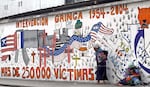 Indigenous women beg in Guatemala in June 2004 in front of a propaganda mural that speaks against U.S. interventions in the region.