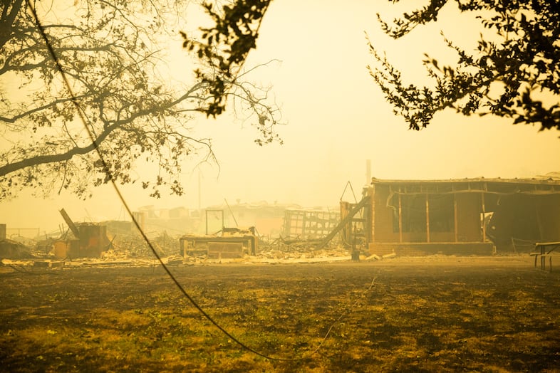 A downed power line runs to the charred husk of a building at the former site of the incident command center for the Santiam Fire near Gates, Ore., Sept. 9, 2020. Wind helped expand the Beachie Creek Fire, now the Santiam Fire, to a 130,000-acre blaze by Wednesday.