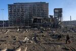 A man walks with his dog amid the destruction caused after shelling of a shopping center, in Kyiv, Ukraine, Monday, March 21, 2022. (AP Photo/ (AP Photo/Rodrigo Abd)
