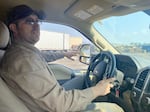 The interior passenger side view of a man sitting behind the wheel of his pickup truck.