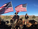 Mourners on horseback held American flags, waiting for the hearse.