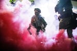 Police and federal officers throw gas canisters to disperse protesters near a U.S. Immigration and Customs Enforcement facility in Portland, Ore., on Sunday.