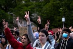 Students and protesters raise peace signs in the air while listening to speakers at the encampment for Palestine on Tuesday, May 7, 2024, at the University of Washington Quad in Seattle. Large crowds amassed ahead of a speech by Turning Point USA founder Charlie Kirk at the HUB on UW's campus.