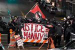 A protester carries a flag that reads "Antifascist Action" near a banner that reads "Justice for Manny," during a protest against police brutality, late Sunday, Jan. 24, 2021, in downtown Tacoma, Wash., south of Seattle.