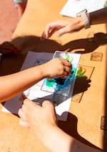 Yao Cheng, right, helps a child make prints at the crafts station.