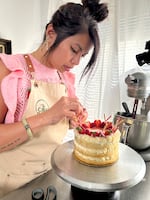 Baker Helen Hồng Nguyễn, also known as "The Cake Batch" on social media, decorates a vanilla-and-berry cake in her home studio in Beaverton, Ore., on April 18, 2025.