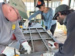 Don Allen (left) and historic window specialist Chris Gustavson (right) and volunteers of the Sand Mountain Society repair 95-year-old vintage windows damaged by vandals in June.