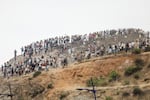 Migrants attempting to cross into Spain's North African enclave of Ceuta gather on a hilltop during clashes with Moroccan security forces near the town of Fnideq, on the Morocco-Spain border, on Friday. The European Union on July 31 scrambled to contain one of the largest migrant crises faced by the block in recent years, after tens of thousands of people poured into into Spain's North African Ceuta enclave in just days.
