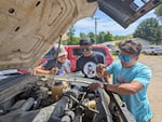Jalisco Miles, left, holds a checklist while Farrell Hayes, middle, and Riston Bullock, right, check on the fire truck engine on June 12, 2025.