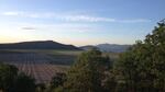 Farmland framed by trees in the foreground and low rolling mountains in the distance.