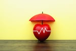 A photo illustration shows an apple with an EKG line across it, covered by an umbrella. 