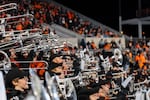 A crowd of marching band members lift shiny silver instruments.