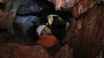 Neil Marchington peering into a hole in No Name Cave.