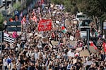 Students with a large red banner reading 'Police officers, enemy of the people' march during a protest against under-resourced schools, in Rennes, western France, Tuesday, Oct. 6, 2026.