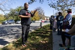 Standing outdoors near federal workers lined up on a sidewalk, Pastor Oliver Carter explains the procedures for the food distribution.