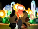 A child wearing a mask stands near light decorations at a mall in Beijing on Friday. China is on a bumpy road back to normal life as schools, shopping malls and restaurants fill up again following the abrupt end of some of the world's most severe restrictions even as hospitals are swamped with COVID-19 patients.