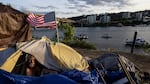 A man named Frank sits in his tent with a river view in Portland, Ore., in 2021. A lawsuit originally filed in 2018 on behalf of homeless people in the Oregon city of Grants Pass is set to go before the U.S. Supreme Court in April.