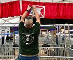 Cliff Bergstrom hangs the first-place ribbon won by his daughter, Erika, in a Class 3 market hog competition at the Clackamas County Fair in Canby, Oregon, on opening day Aug. 14, 2018.