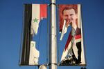 A billboard bearing a picture of Syria's President Bashar al-Assad and a national flag are torn by antigovernment fighters in the northern city of Aleppo on Nov. 30.