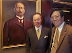 FILE - Brothers James and David Louie, co-owners of Portland's oldest restaurant, standing with a portrait of its namesake, Frank Huber, in 2014. James Louie, left, died this week, but the restaurant continues to be operated by the family.