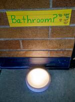 a light on the floor, with a sign above it reading bathroom, yes, light on, no, light off.