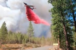 In this photo provided by the Bootleg Fire Incident Command, a tanker drops retardant over the Mitchell Monument area at the Bootleg Fire in southern Oregon on Saturday, July 17, 2021.
