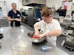 Audrey Duewall mixes strawberries with sugar for her almond butter and fruit cookie cups, while her helper Carlie Shute looks on.