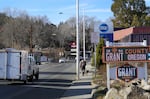 Cars and pedestrians travel down the highway as a bright green and yellow sign advertises the Grant County Chamber of Commerce.