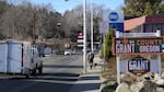 Cars and pedestrians travel down the highway as a bright green and yellow sign advertises the Grant County Chamber of Commerce.